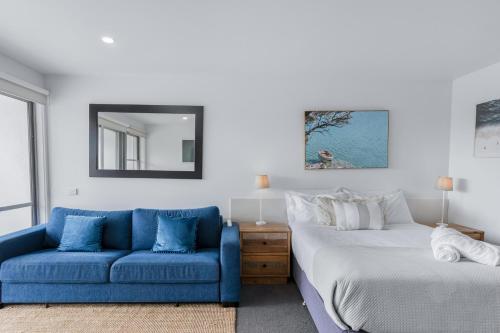 a bedroom with a bed and a blue couch at Bay View - Ocean Nest in Lorne