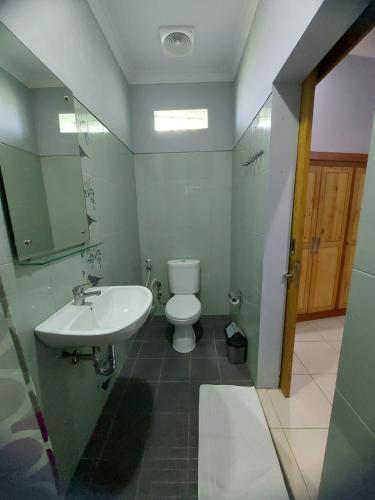 a bathroom with a white toilet and a sink at Hamemayu Homestay in Jejeran