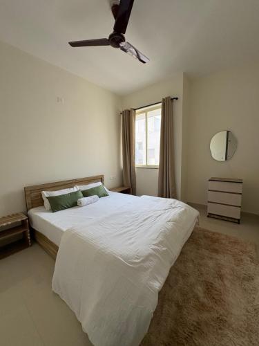 a bedroom with a white bed with a ceiling fan at Live Easy in Mātigara