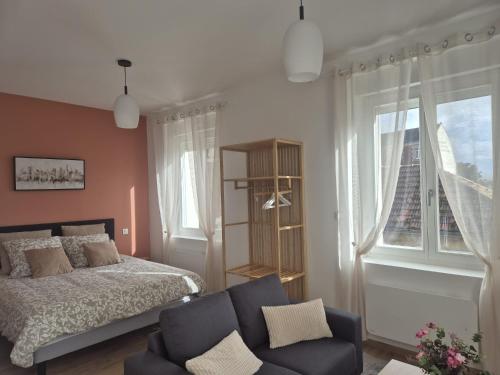 a bedroom with a bed and a couch and a window at le st fursy 1 in Péronne