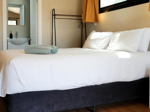 a large bed with white sheets and pillows at Parkes Cabins in Parkes