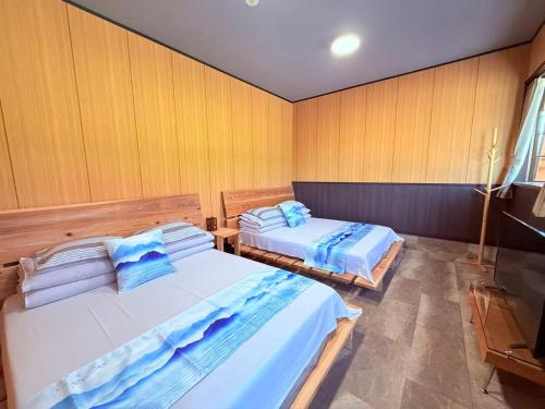 two beds in a room with wooden walls at Shanshui House TAKASHIMA 一棟貸切 自炊BBQok in Takashima