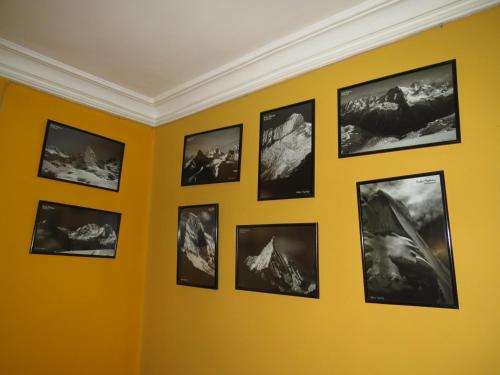a wall of pictures on a yellow wall at La Casa de Zarela in Huaraz