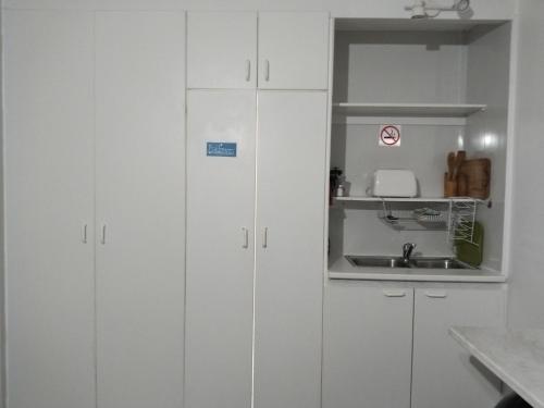 a kitchen with white cabinets and a sink at Ryans Surf Cabin in Jeffreys Bay