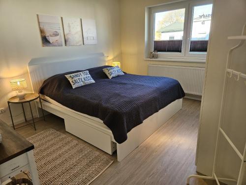 a bedroom with a bed with blue sheets and a window at Küstenglück 2 Stylisches Apartment mit Meerblick - 200m zum Strand & Bäcker in Dahme