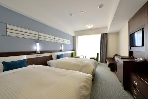 a hotel room with two beds and a flat screen tv at Vessel Hotel Campana Okinawa in Chatan