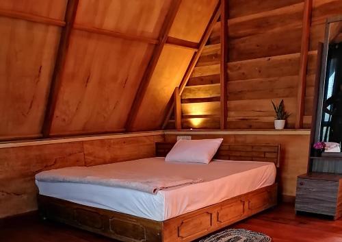 a bed in a room with a wooden ceiling at The Cliff Lodge Ella in Ella