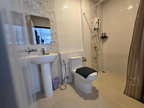 a white bathroom with a sink and a toilet at Charma Home Watket in Chiang Mai