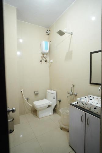 a white bathroom with a toilet and a sink at Frolic Hotel Near Sec 52 Noida Metro Station in Noida