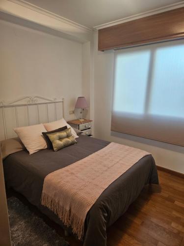 a bedroom with a large bed with a large window at apartamento castelao in Cedeira