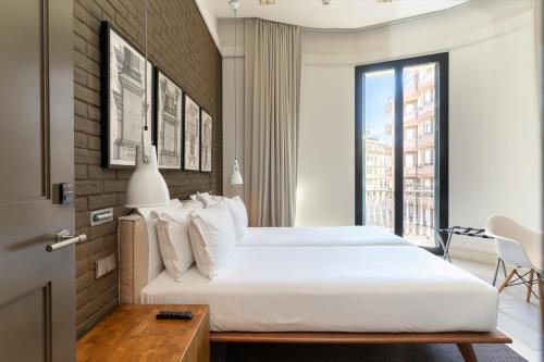 a bedroom with a large white bed and a window at Midtown Apartments in Barcelona