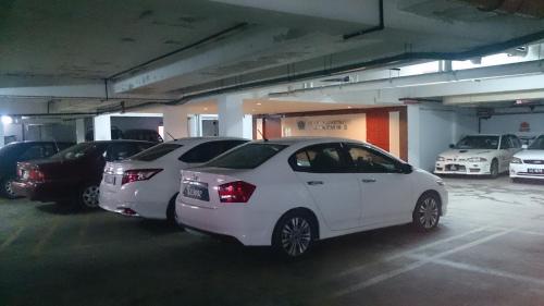 two white cars parked in a parking lot at Hotel & Apartment Ambassador 3 in Labuan