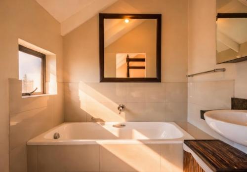 a bathroom with a tub and a sink and a mirror at 19 Lagoon Terrace in Knysna