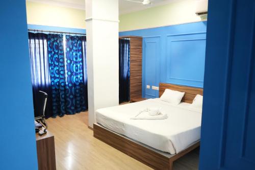 a bedroom with a white bed with blue walls at Royal Homes in Tallākulam