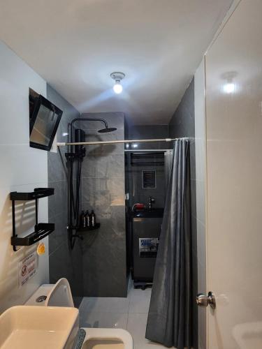 a small bathroom with a shower and a sink at Ohhlala Cozy Corner at Royal Oceancrest Mactan in Mactan Island