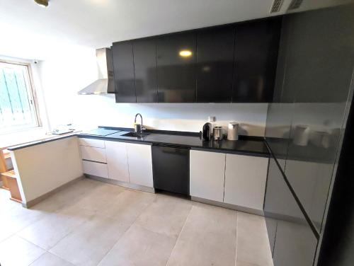 a kitchen with black and white cabinets and a sink at Lisbon Airport GuestHouse GAL Olivais Conforto, Terraço e Localização Premium nos Olivais in Lisbon
