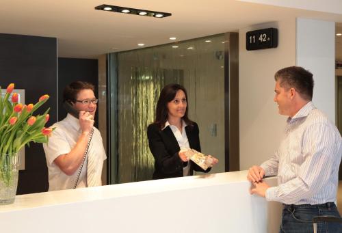 a group of people standing around a reception counter at Hôtel Alba in Lourdes