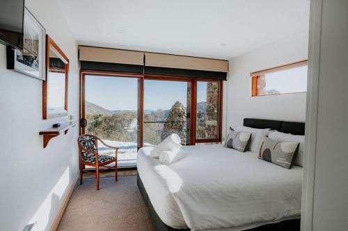 a bedroom with a bed and a large window at Alpine Woodsmoke Apartments in Falls Creek