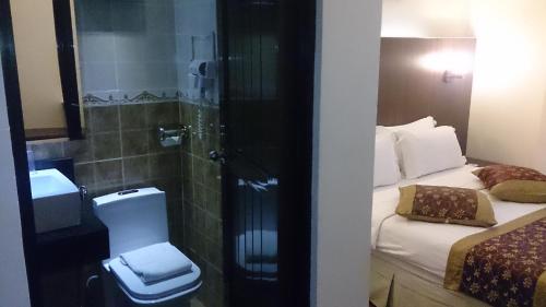a bathroom with a bed and a shower and a toilet at Hotel & Apartment Ambassador 3 in Labuan
