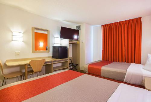 ein kleines Hotelzimmer mit 2 Betten und einem Schreibtisch in der Unterkunft Motel 6-Whitby, ON - Toronto East in Whitby