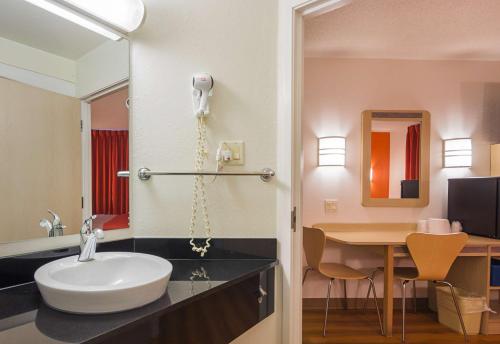 a bathroom with a sink and a desk with a mirror at Motel 6-Whitby, ON - Toronto East in Whitby
