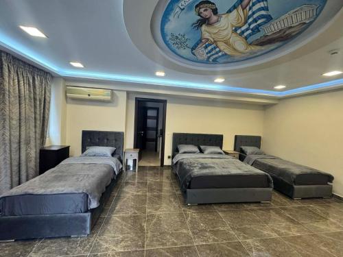 a room with three beds and a painting on the ceiling at Imperia President in Paralia Katerinis