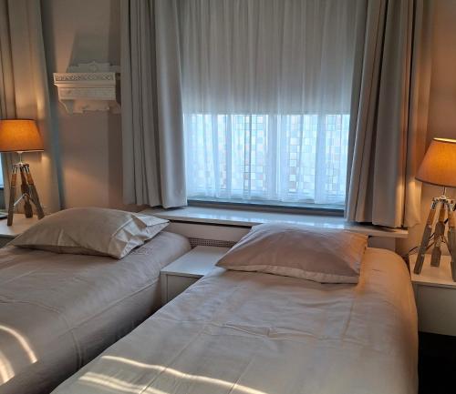 two beds sitting in a room with a window at LandLust Guesthouse B&B Amsterdam Area Purmerend in Purmerend