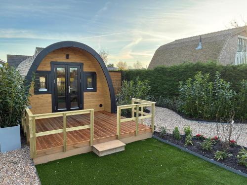 a tiny house with a wooden deck in a garden at Bungalowverhuur 't Lappennest in Noordwijk