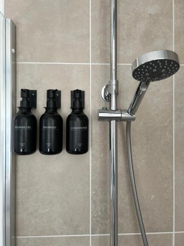 a shower with three black bottles on the wall at Lésina Bed & Breakfast in Apt