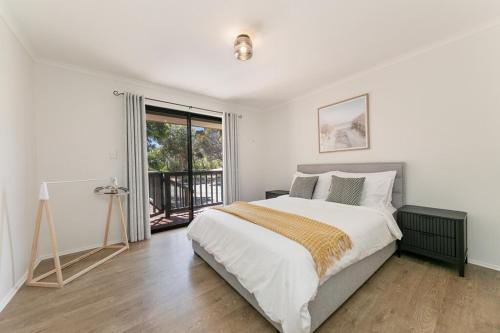 a white bedroom with a large bed and a window at Viaggio Sul Mare in Baudin Beach