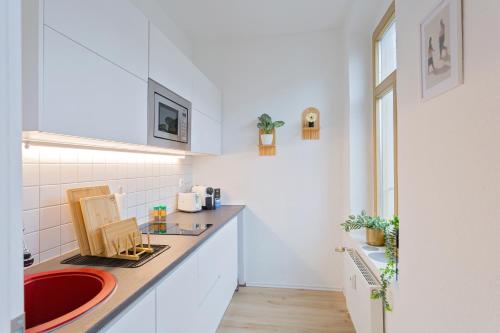 a kitchen with white cabinets and a red sink at Stadtoase Chemnitz in Chemnitz