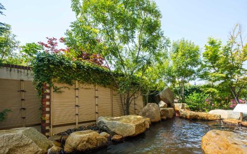a garden with a pond with rocks and a fence at Hotel Okura JR Huis Ten Bosch in Sasebo