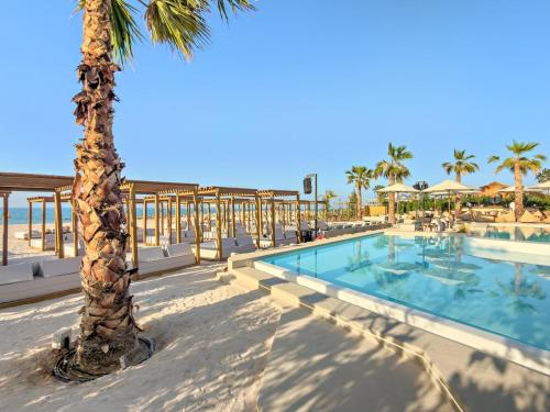 Una palmera y una piscina en un resort. en FIRST CLASS Studio Stunning Beachfront Bliss, en Ras al Khaimah