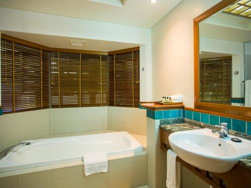a bathroom with a tub and a sink and a mirror at Green Island Resort in Green Island