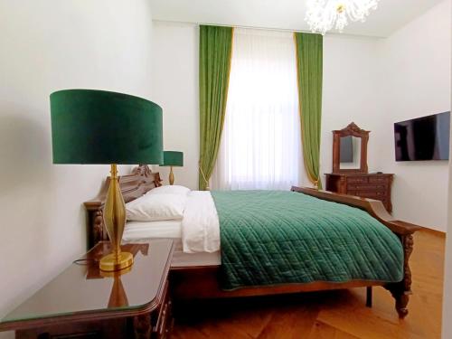 a bedroom with a bed with a green blanket and a lamp at Casa Doseanu , Stern Palace Historic Residence in Oradea