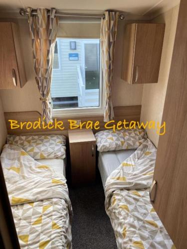 a small room with two beds and a window at Brodick Brae Getaway in Dunure