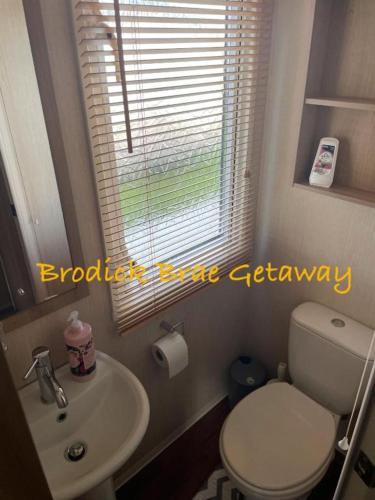 a bathroom with a toilet and a sink and a window at Brodick Brae Getaway in Dunure