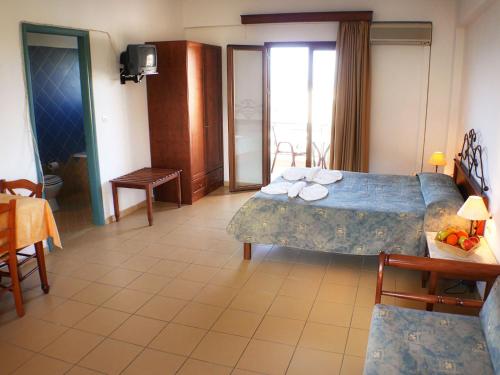 a hotel room with two beds and a table and chairs at Areti Aparthotel in Áptera