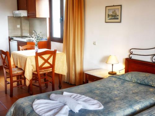 a bedroom with a table and a kitchen with a table and chairs at Areti Aparthotel in Áptera