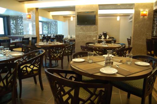 a restaurant with wooden tables and chairs and a television at Comfort Inn President Near Ahmedabad Junction Station in Ahmedabad