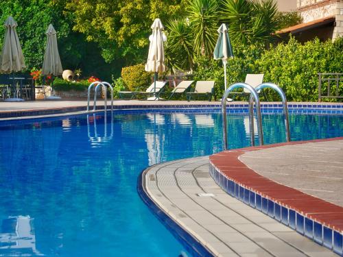 a swimming pool with chairs and umbrellas in a resort at Areti Aparthotel in Áptera
