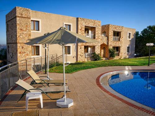 a patio with two chairs and an umbrella next to a pool at Areti Aparthotel in Áptera