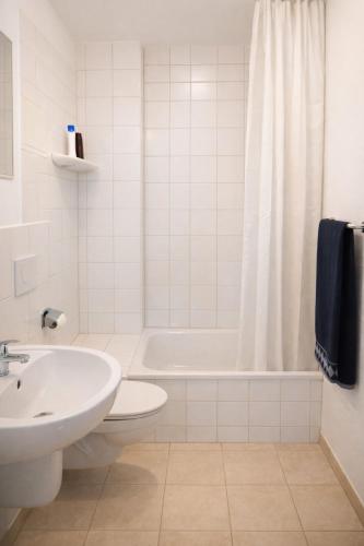 a white bathroom with a tub and a sink at Königstein Hostel in Königstein an der Elbe