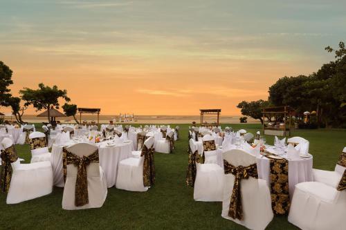 a wedding reception with white chairs and tables with the ocean in the background at Ayodya Resort Bali in Nusa Dua