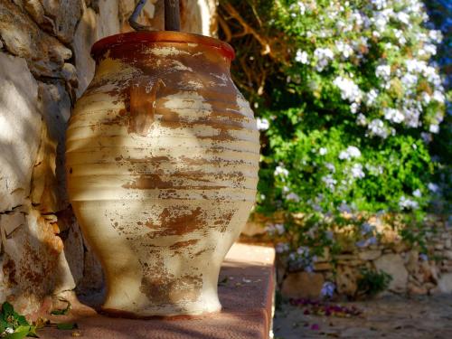 a vase sitting on a stand next to a tree at Areti Aparthotel in Áptera