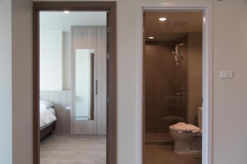 a bathroom with a toilet and a glass door at The View Chaengwattana 14 in Bangkok
