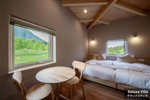 a bedroom with a bed and a table and a window at Rusutsu Hills CENTRO in Rusutsu