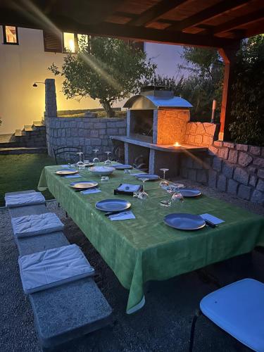 a table with a green table cloth and a fireplace at Sea view villa with large garden in Campo nell'Elba
