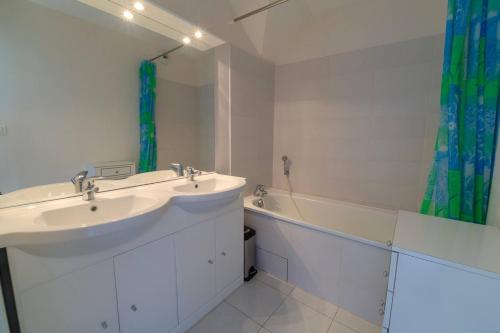 Un baño con dos lavabos y una bañera y un lavabo. en Isabelle, en Stella-Plage