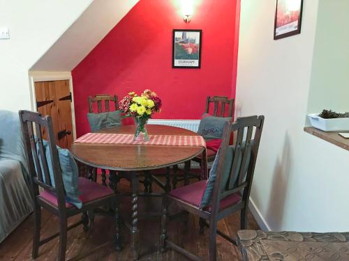 a dining room table with a vase of flowers on it at Isabella Cottage in Heddon on the Wall